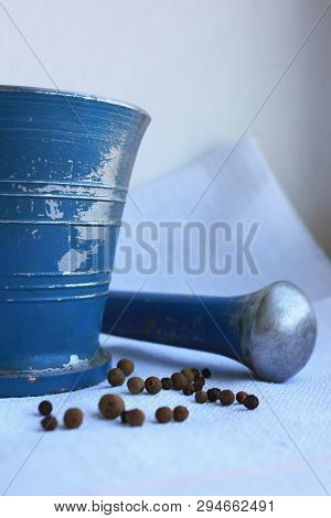 Black Peppercorns And Allspice In Ancient Metal Mortar With Pestle On Linen Background