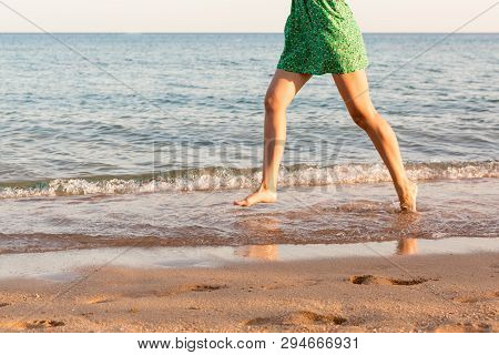 Leg Of Woman Running On Beach With Water Splashing. Summer Vacation. Legs Of A Girl Walking In Water