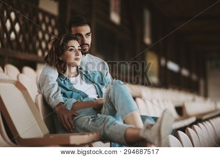 Portrait Of Romantic Couple Sitting Together On Empty Sports Tribune