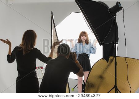 Photographer And Stylist Team Working On Studio Portrait Of Young Beautiful Asian Woman With Dark Br