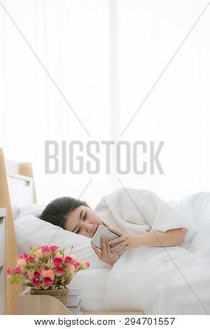 Young And Beautiful Asian Woman Sleep In Bed And Using Smartphone After Awake With Copy Space On Top