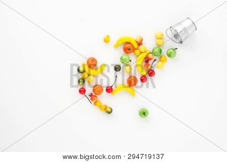 A Scattering Of Many Small Different Fruits On A White Background. Mini Copy Of A Metal Bucket. The 