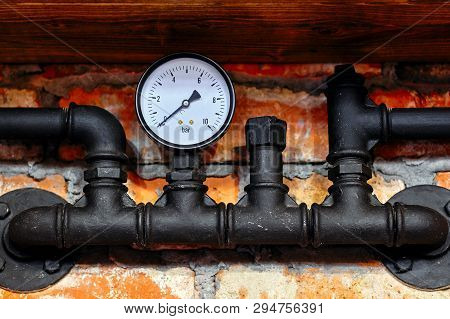 Old Black Pipeline Pressure Gauge Close Up Against A Brick Wall Background