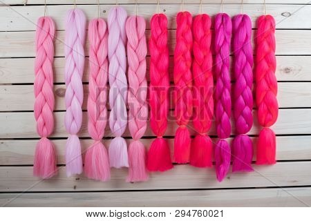 Kanekalon Hangs On A Wooden Background Of Pink, Fuchsia Red In Different Shades Similar