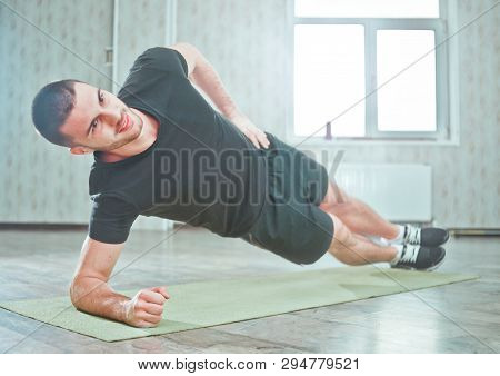 Healthy Sporty Man Doing Indoor Side Plank Exercise On Mat, Static Exercise