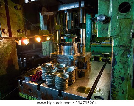 Dirty Used Low Tech Stamping Press Producing Round Aliminium Parts In Dark Environment