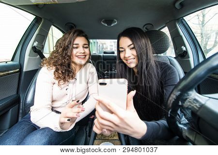 Two Young Women Hangout On Car Trip Driving The Car And Taking Selfie