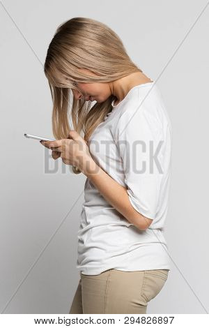 Close Up Portrait Of Young Caucasian Female Looking And Using Smart Phone With Scoliosis, Side View/