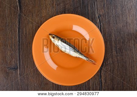 Cold Smoked Baltic Herring On An Orange Plate Over A Wooden Background. Smoked Baltic Herring Smoked
