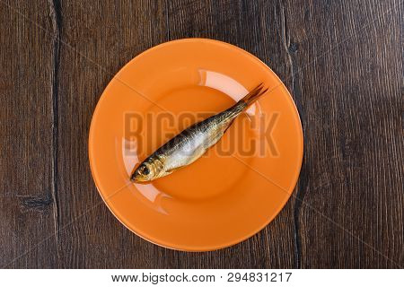 Cold Smoked Baltic Herring On An Orange Plate Over A Wooden Background. Smoked Baltic Herring Smoked
