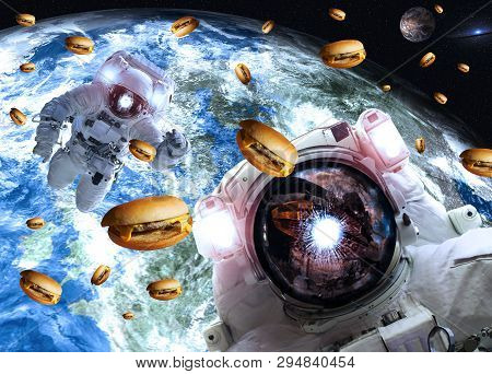 Astronauts In Outer Space With Cheseburgers On The Earth And Marts Planets On The Background. Scienc