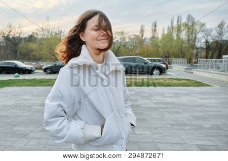 Outdoor Portrait Of Teenager Girl 15 Years Old, Girl Smiling With Long Brown Hair In White Jacket.