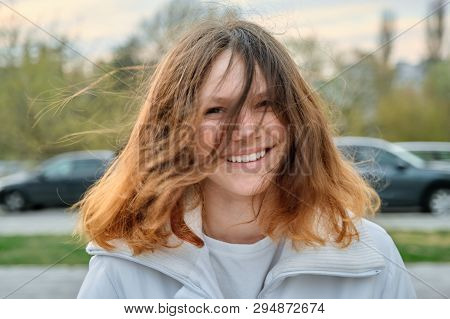 Outdoor Portrait Of Teenager Girl 15 Years Old, Girl Smiling With Long Brown Hair In White Jacket.