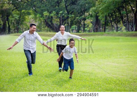 Happy Asian Family, Parents And Their Children Running Around  In Park Together. Father Mother And S