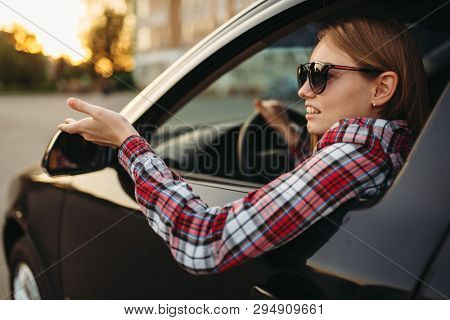 Female car driver in sunglasses, boorish behavior