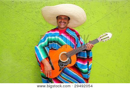 Messicano tipico uomo suona la chitarra con poncho in parete verde