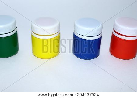 Jars With Gouache Paint, Four Different Colors: Green, Yellow, Blue, Red On A White Background