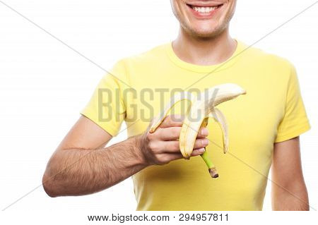 Smiling Handsome Guy Holding Yellow Banana Over White Background. Studio Shot.