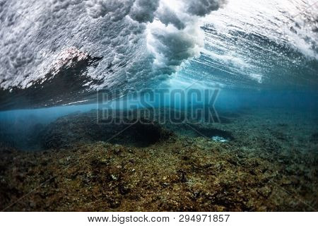 Underwater view of the ocean wave breaking over the shallow part of the coral reef at Honkeys surf spot in the Maldives