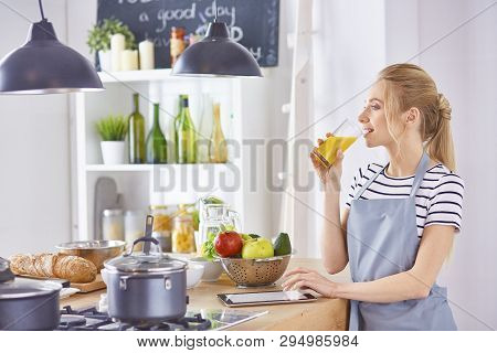 The Girl At The Table In The Kitchen With A Glass Of Orange Jui