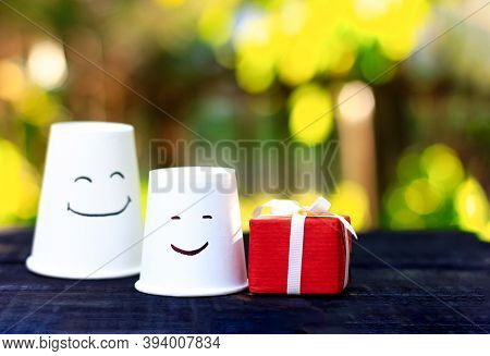 Large And Small Disposable Cups With Emotions Of Pleasure And Red Holiday Box. Symbol Of The Relatio