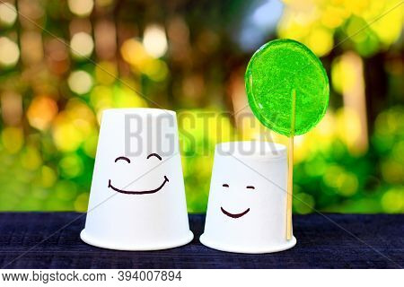 Two Smiling Cups With Green Lollipop. Emotion Of Joy, Symbol Of Friendship