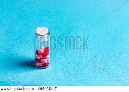 Red-pink Pills In A Glass Jar On A Blue Background. Pharmaceuticals.