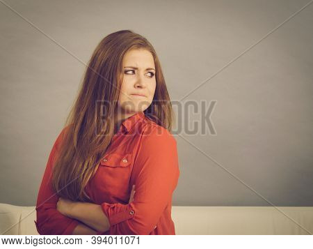 Angry, Pissed Off Young Woman. Attractive Female With Long Brown Hair Sitting On Sofa Being Mad And 