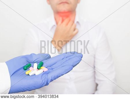 The Doctor Holds Pills In His Hand Against The Background Of A Man With A Diseased Thyroid Gland. Th