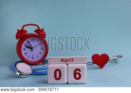 April 6st. White Wooden Calendar Blocks With Date, Clock And Stethoscope On A Blue Pastel Background