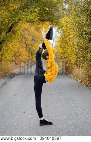 The Concept Of Grace And Beauty In Gymnastics. View Of A Girl Standing In A Vertical Twine Against T
