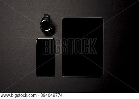 Overhead Shot Of A Smartwatch, Smartphone And A Tablet On A Black Background. Wireless Technology Co
