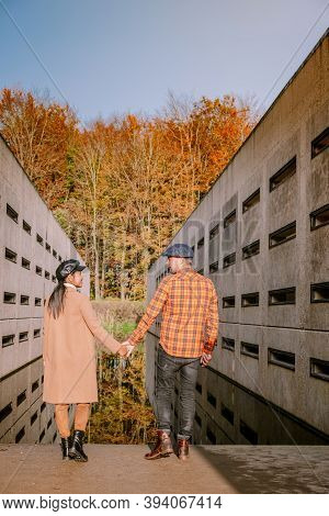 Couple Men And Woman Hiking In The Forest During Autumn And Small Streaming Water River With Fall Co