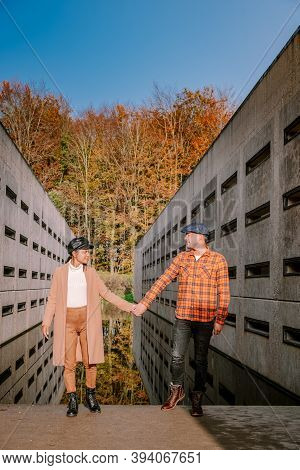 Couple Men And Woman Hiking In The Forest During Autumn And Small Streaming Water River With Fall Co