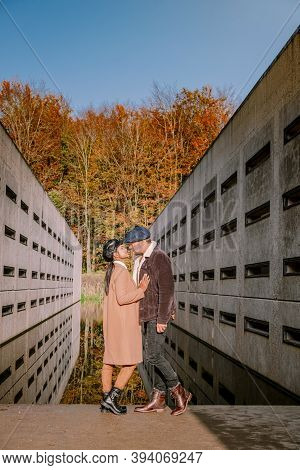 Couple Men And Woman Hiking In The Forest During Autumn And Small Streaming Water River With Fall Co