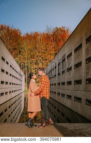 Couple Men And Woman Hiking In The Forest During Autumn And Small Streaming Water River With Fall Co