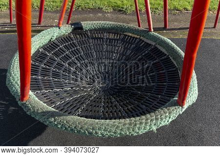 A Close Up View Of A Plastic, Metal And Rubber Swing In A Open Play Area