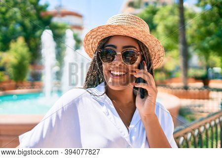 Young african american woman with braids smiling happy spaking on the phone outdoors on a sunny day of summer