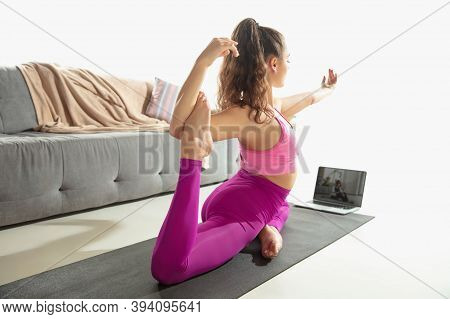 Inspired. Beautiful Young Woman Working Out Indoors, Doing Yoga Exercise On Gray Mat At Home. Long H