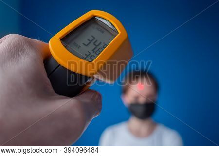 Measurement, Healthcare, Infection, Coronavirus Concept. Man Hand Holding Yellow Pyrometer And Measu