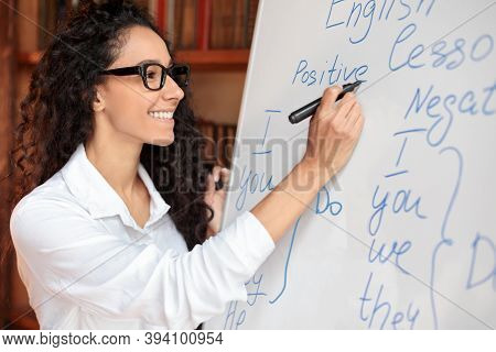 Education Cocnept. Smiling Professional English Teacher Standing At Whiteboard, Writing With Marker.