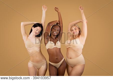 Love Your Body. Happy Three Women With Different Shapes And Appearance Posing Over Beige Studio Back