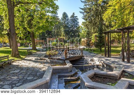 Razlog, Bulgaria - October 20, 2020: Downtown Street Panoramic View With Cafe, Autumn Trees And Foun