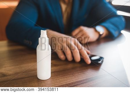 Antiseptic On The Background Of The Hands Of A Businessman Take The Phone On The Table