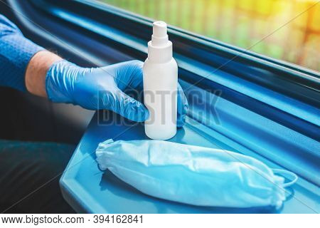 A Man's Hand In A Medical Glove Takes An Antiseptic Next To A Protective White Mask, Soft Focus
