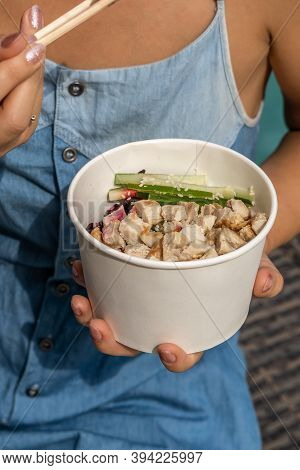 Woman Sitting By The Pool Against Blue Water Background With Chopsticks And Eating Takeout Healthy O