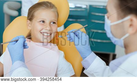 Modern Painless Dental Treatment For Children. Doctor In Protective Mask, White Coat And Rubber Glov