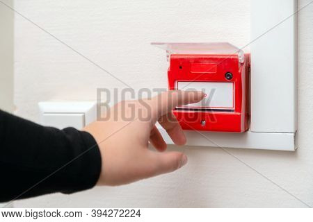 Hand Pressing Fire Alarm Button At School Or Business Office. Close Up Of Protection Console Against