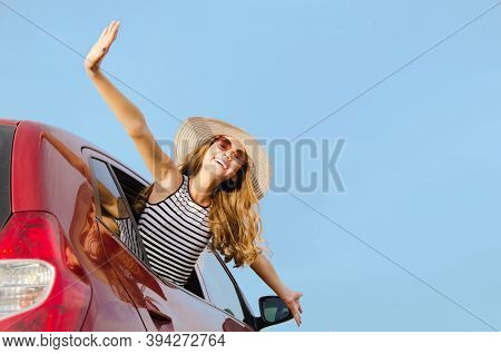 Cute Happy Smiling Little Girl Child Goes To Summer Travel Trip In The Red Car. Preteen In Hat And S