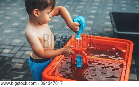 Caucasian Boy With Undressed Belly Is Playing With Water And Plastic Toys